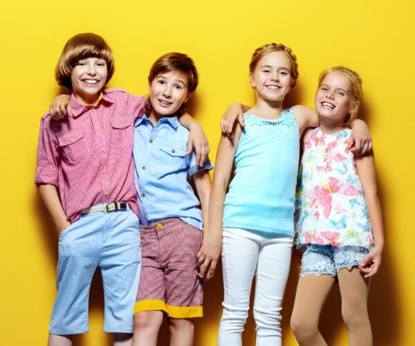Bright summer children. Group of joyful children posing together over bright yellow background.